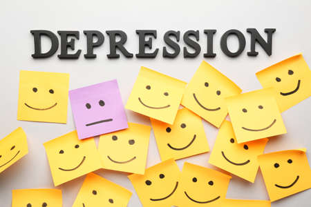 One sticky note with drawn neutral face among happy ones on light background. Concept of depressionの写真素材