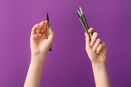 Female hands with pens on color backgroundの写真素材