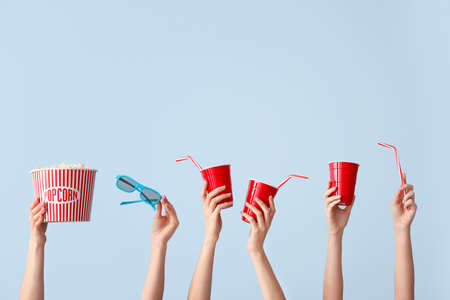 Many hands with popcorn, drink and eyeglasses on color backgroundの写真素材