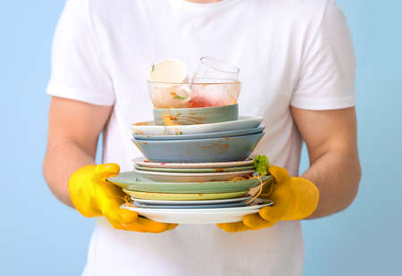Man with dirty dishes on color backgroundの写真素材