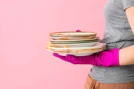 Woman with dirty dishes on color backgroundの写真素材