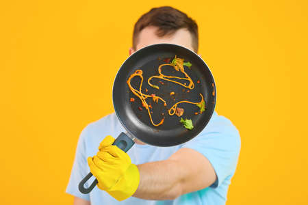 Man with dirty frying pan on color backgroundの写真素材