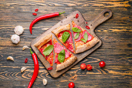 Board with slices of tasty pizza on wooden tableの写真素材