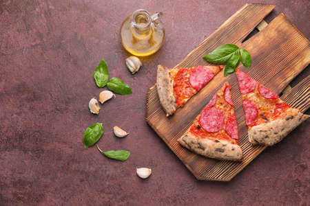 Board with slices of tasty pizza on color backgroundの写真素材