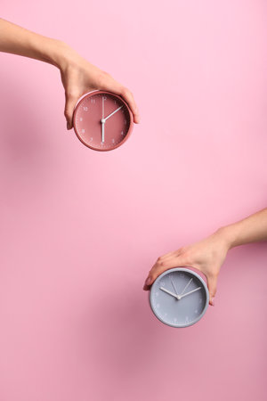 Female hands with clocks on color background. Time management conceptの写真素材