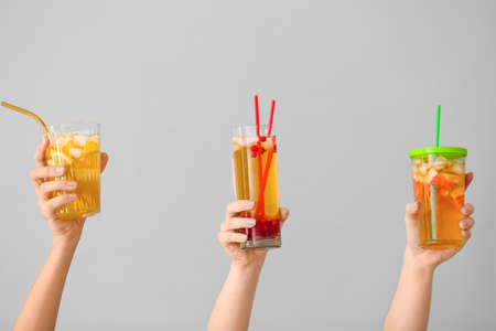 Female hands with cold tea in glasses on gray backgroundの写真素材