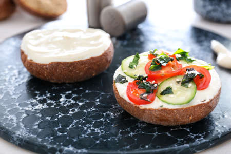 Fresh bun with tasty cream cheese and vegetables on tableの写真素材