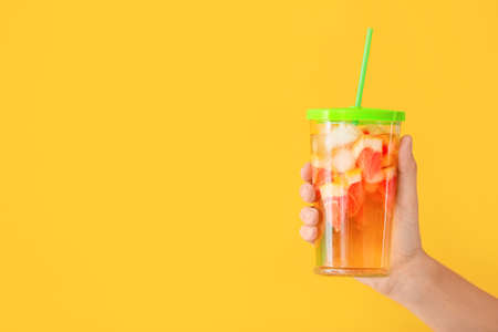 Female hand with cold tea in glass on color backgroundの写真素材