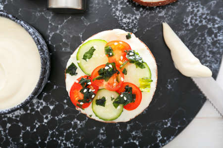 Fresh bun with tasty cream cheese and vegetables on tableの写真素材