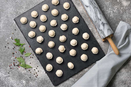 Raw fresh dumplings with rolling pin on gray backgroundの写真素材