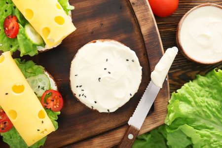 Fresh bun with tasty cream cheese and sandwiches on boardの写真素材