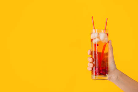 Female hand with cold tea in glass on color backgroundの写真素材