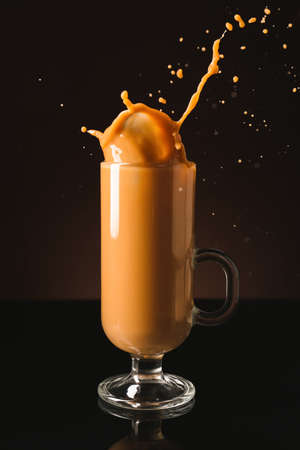 Splashing of coffee in glass cup on dark backgroundの写真素材