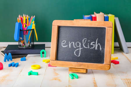 Chalkboard with text ENGLISH and stationery on table in classroomの写真素材