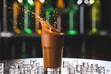 Splashing of coffee in glass on dark backgroundの写真素材