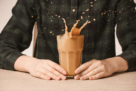 Woman with glass of splashing coffee in on tableの写真素材