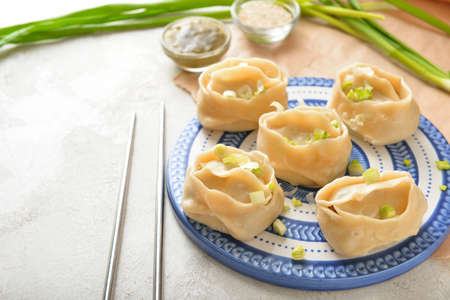 Plate with oriental dumplings and onion on light backgroundの写真素材