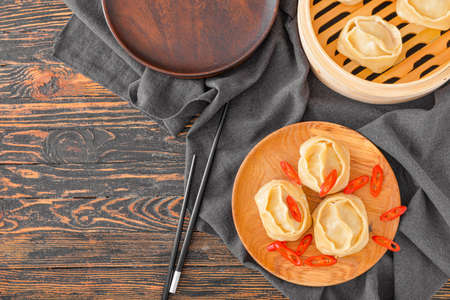 Plate with oriental dumplings and chili pepper on table