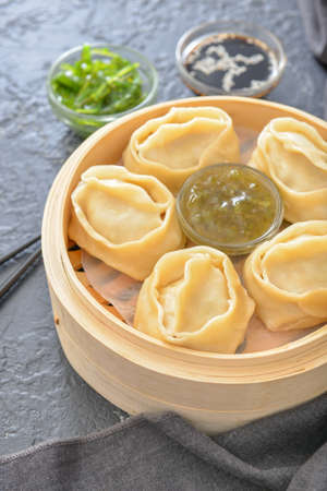 Steamer with oriental dumplings and sauce on dark backgroundの写真素材