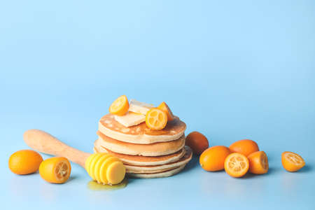 Tasty pancakes with honey, butter and citrus fruit on color backgroundの写真素材