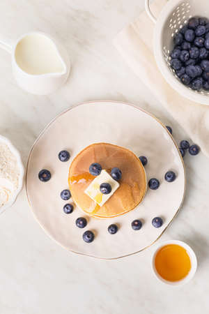 Tasty pancakes with honey, butter and berries on tableの写真素材