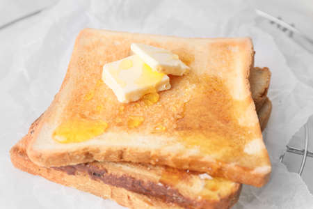 Tasty toasted bread with honey and butter on cooling rack, closeupの写真素材