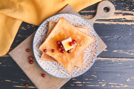 Tasty toasted bread with honey, butter and berries on plateの写真素材