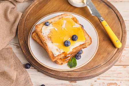 Tasty toasted bread with honey, butter and berries on tableの写真素材