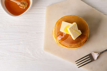 Tasty pancakes with honey and butter on tableの写真素材
