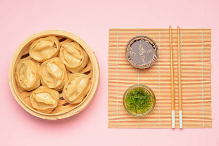 Steamer with oriental dumplings and sauce on color backgroundの写真素材