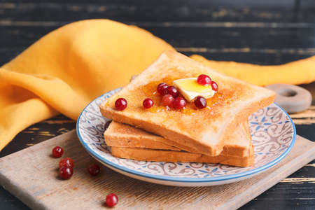 Tasty toasted bread with honey, butter and berries on plateの写真素材