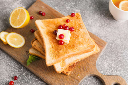 Tasty toasted bread with honey, butter and berries on gray backgroundの写真素材