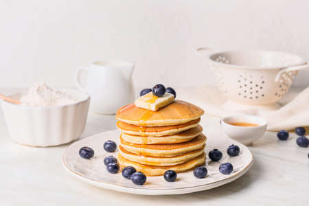 Tasty pancakes with honey, butter and berries on tableの写真素材