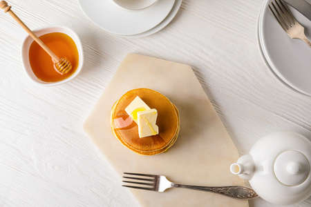 Tasty pancakes with honey and butter on tableの写真素材