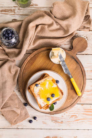 Tasty toasted bread with honey, butter and berries on tableの写真素材