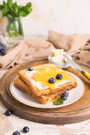 Tasty toasted bread with honey, butter and berries on table