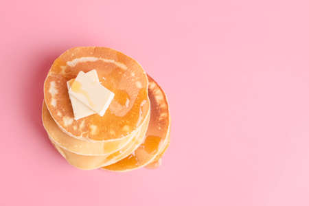 Tasty pancakes with honey and butter on color backgroundの写真素材
