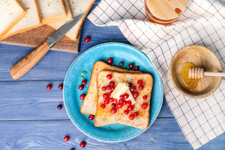 Tasty toasted bread with honey, butter and berries on tableの写真素材