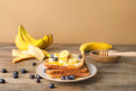 Tasty toasted bread with honey, butter and fruits on plateの写真素材