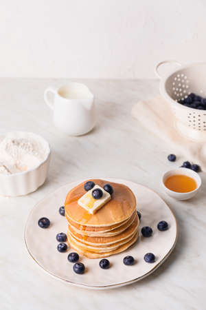 Tasty pancakes with honey, butter and berries on table