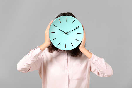 Businesswoman with clock on gray background. Time management conceptの写真素材