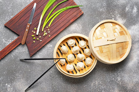 Steamer with tasty dumplings and green onion on gray backgroundの写真素材