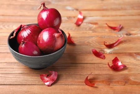Fresh raw onion in bowl on wooden backgroundの写真素材