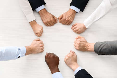 Group of business people putting hands together in office, top view. Unity concept