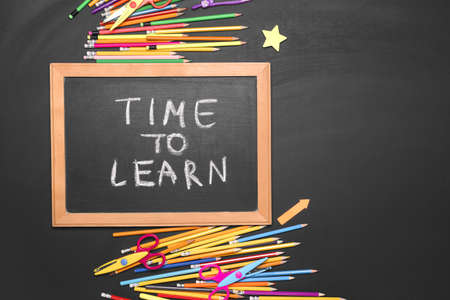 Chalkboard with text TIME TO LEARN and school supplies on dark background