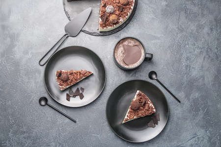 Plates with pieces of tasty chocolate cheesecake and cup of coffee on dark backgroundの写真素材