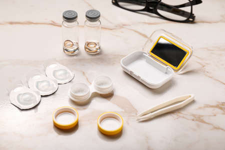 Containers with contact lenses and tweezers on light backgroundの写真素材