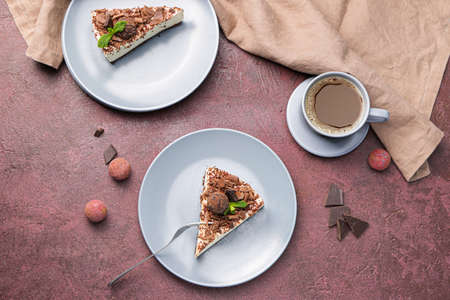 Plates with pieces of tasty chocolate cheesecake and cup of coffee on color backgroundの写真素材