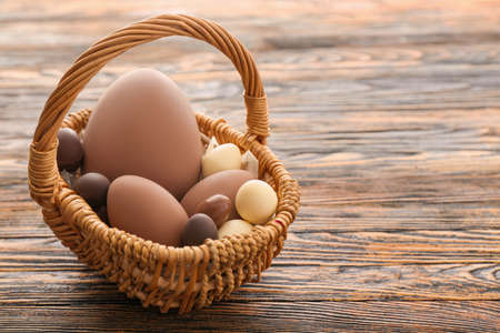 Basket with tasty chocolate Easter eggs on wooden backgroundの写真素材