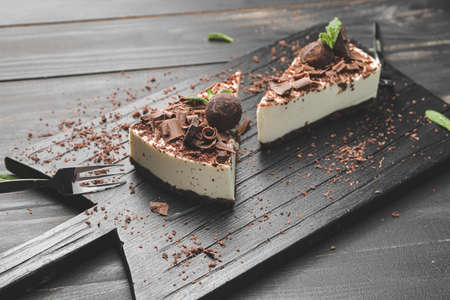 Board with pieces of tasty chocolate cheesecake on dark wooden backgroundの写真素材